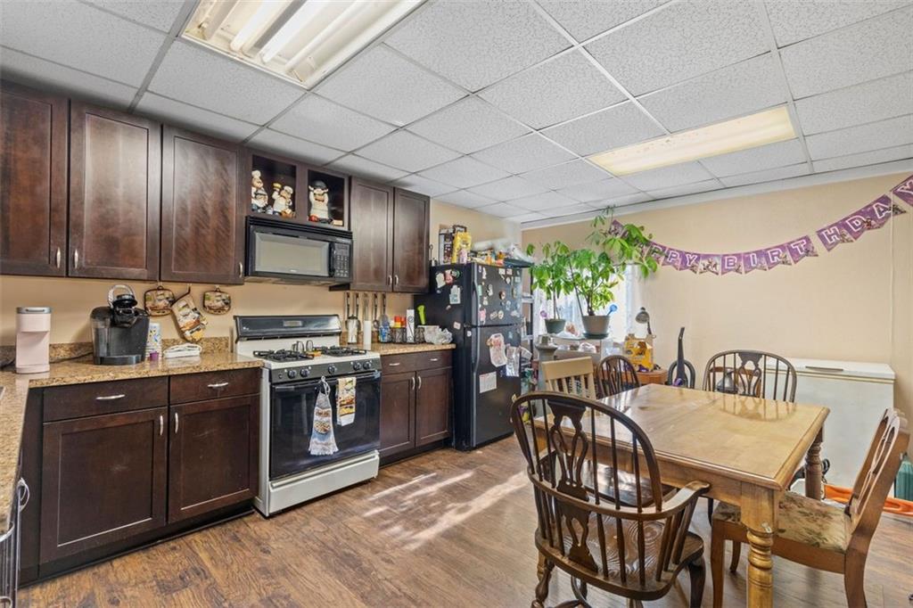 403 Ormsby Avenue Pittsburgh, PA 15210 - Photo 23 of 32 a kitchen with stainless steel appliances granite countertop a stove a sink dishwasher a dining table and chairs with wooden floor