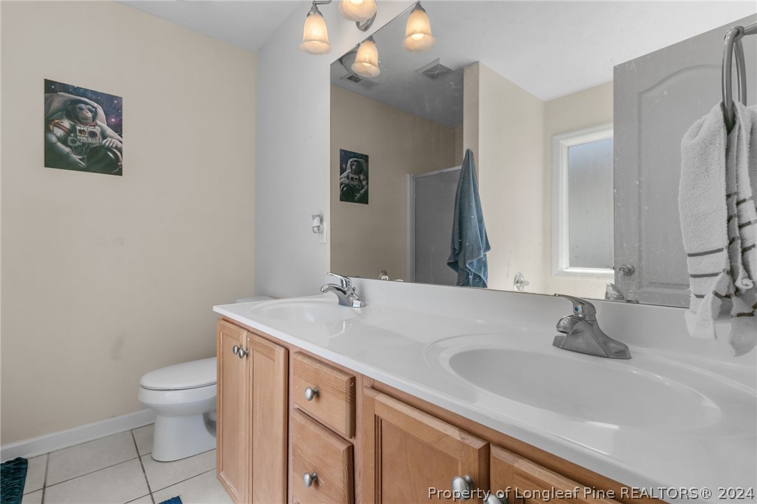 1949 Yellowbrick Road Fayetteville, NC 28314 - Photo 24 of 34 a bathroom with a sink a toilet and mirror