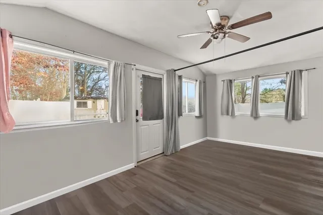 a view of an empty room with a window and wooden floor