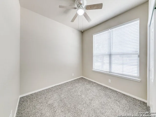 an empty room with windows and fan