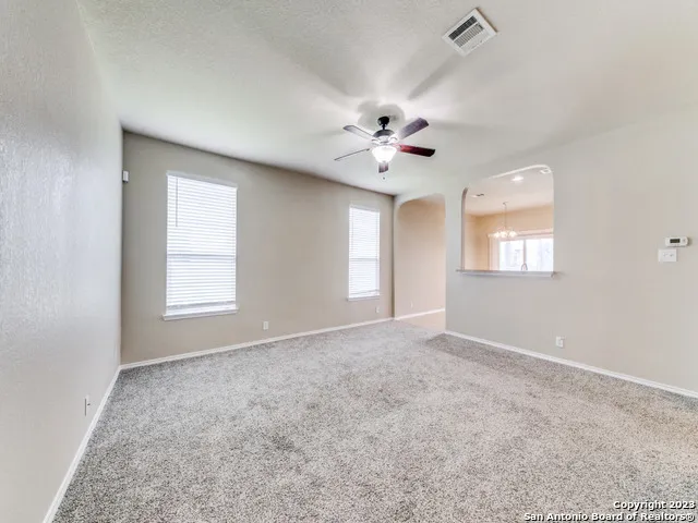 an empty room with windows and chandelier fan