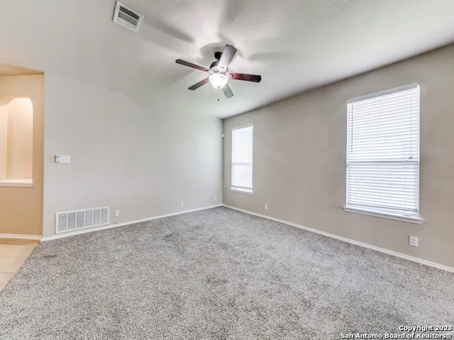 an empty room with windows and fan
