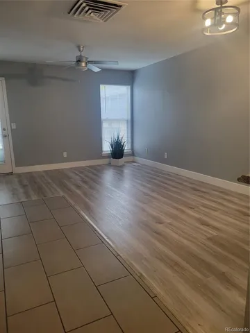 an empty room with wooden floor fan and windows