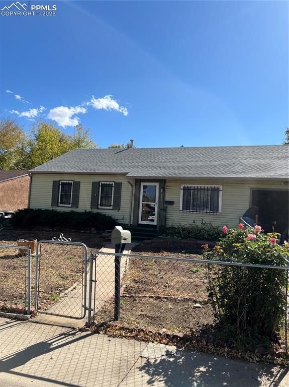 Ranch-style house featuring a gate, a shingled roof, and a fenced front yard