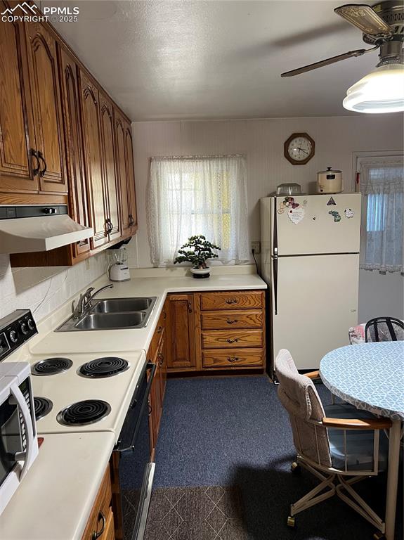 1041 Florence Avenue Colorado Springs, CO 80905 - Photo 25 of 27 Kitchen with stove, brown cabinetry, white fridge, light countertops, and a textured ceiling