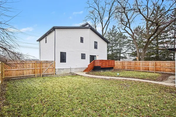 a backyard of a house with wooden fence and large trees