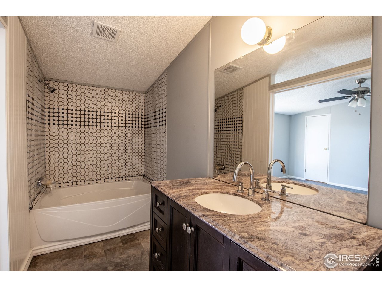4904 Eagle Crest Boulevard, Unit 221 Firestone, CO 80504 - Photo 12 of 25 a bathroom with a granite countertop sink a mirror and a bathtub