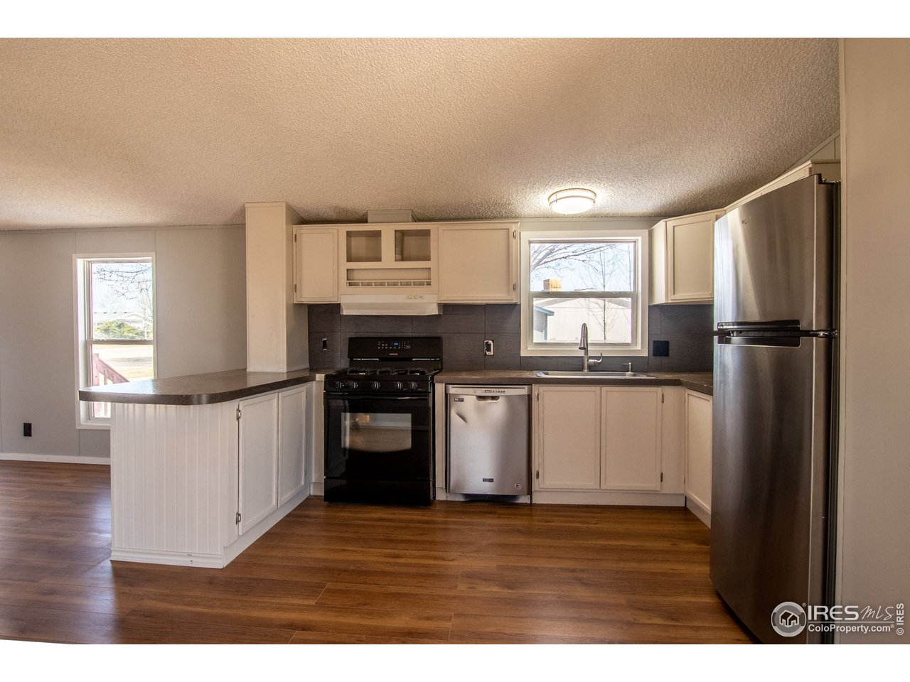 4904 Eagle Crest Boulevard, Unit 221 Firestone, CO 80504 - Photo 4 of 25 a kitchen with a refrigerator and a stove top oven