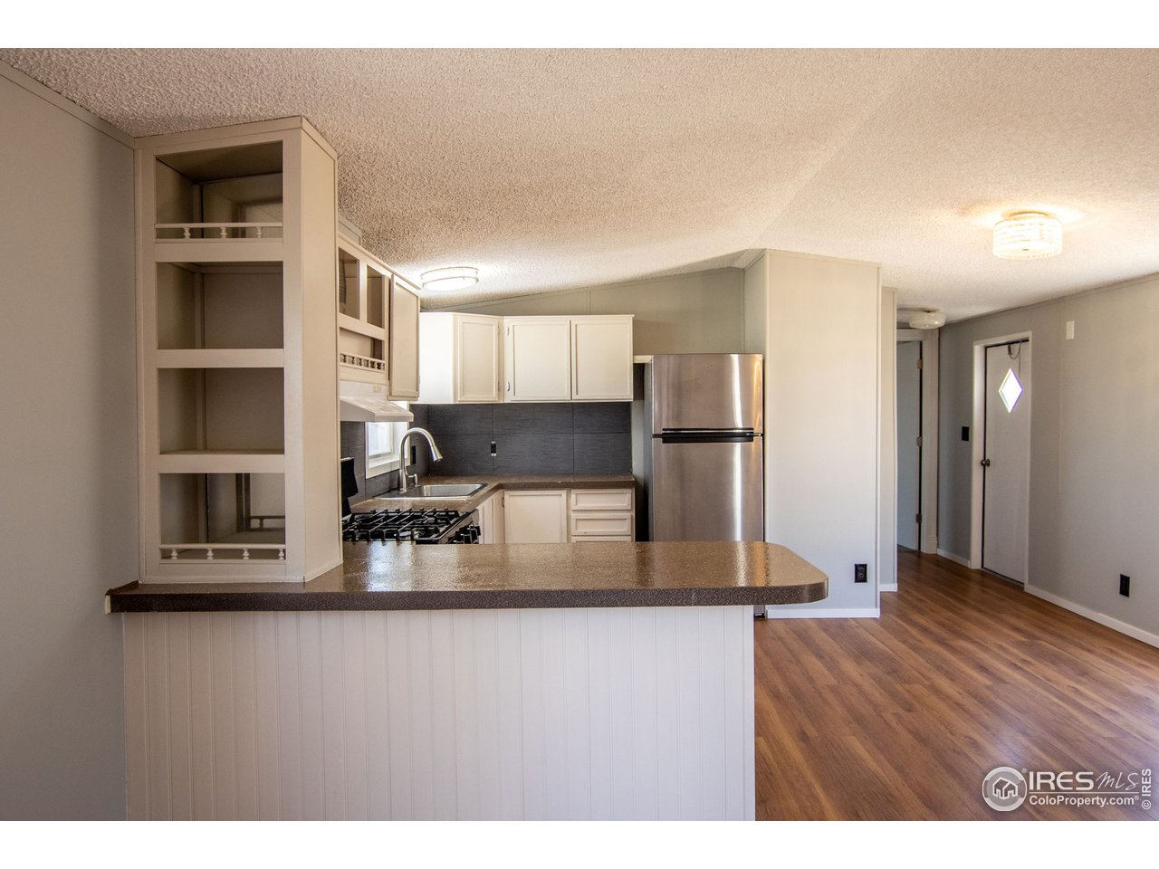 4904 Eagle Crest Boulevard, Unit 221 Firestone, CO 80504 - Photo 9 of 25 a kitchen with stainless steel appliances granite countertop a refrigerator a stove and a sink with wooden floor