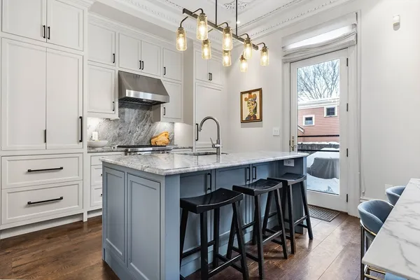 a kitchen with kitchen island granite countertop a table chairs refrigerator and microwave