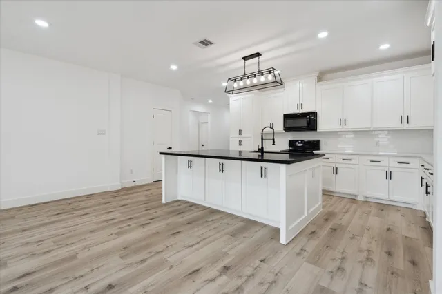 a kitchen with kitchen island a sink stainless steel appliances and white cabinets