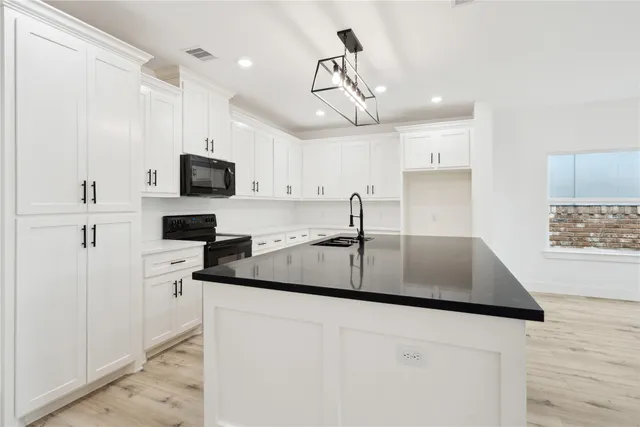 a kitchen with stainless steel appliances a sink a stove a microwave a center island and cabinets