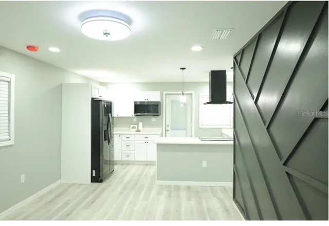 a open kitchen with stainless steel appliances kitchen island granite countertop a refrigerator a stove top oven and sink