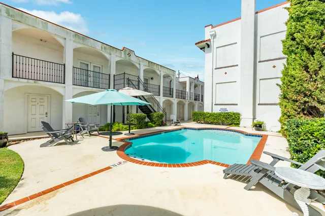 a view of a swimming pool with a table and chairs under an umbrella