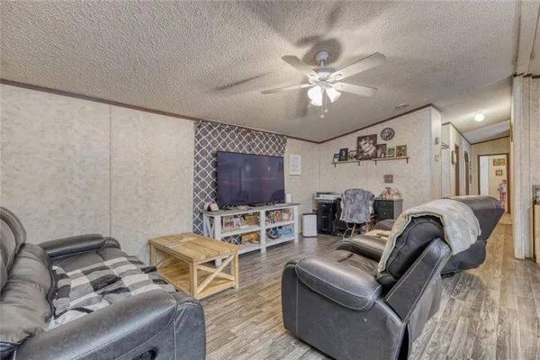 a living room with furniture a flat screen tv and a ceiling fan