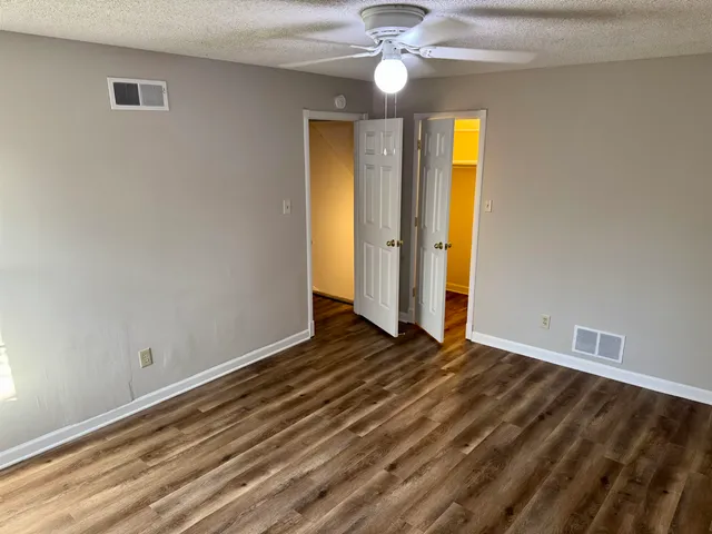 a view of an empty room with window and chandelier fan