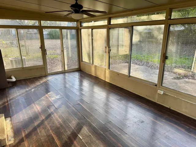 a view of an empty room with wooden floor and a window