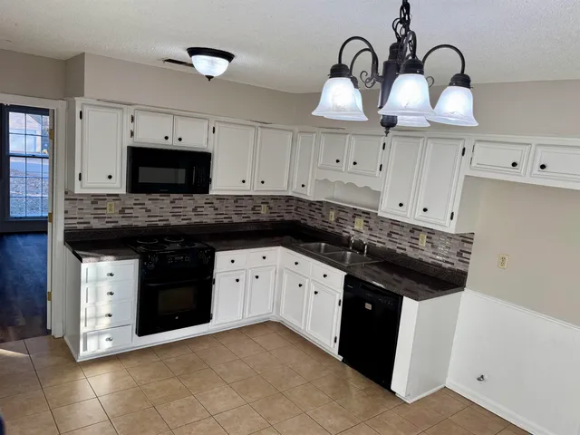 a kitchen with granite countertop white cabinets and stainless steel appliances
