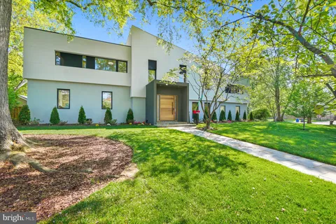 a view of a brick house with a big yard and large trees