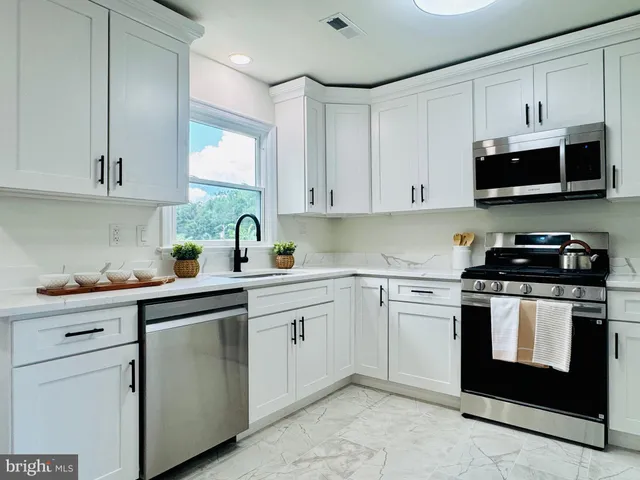 a kitchen with stainless steel appliances granite countertop a sink a stove and a microwave