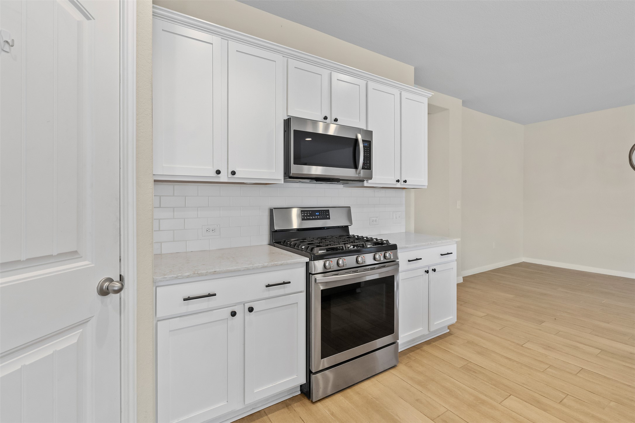 4125 Buffalo Ford Road Georgetown, TX 78628 - Photo 4 of 28 Kitchen with stainless steel appliances, backsplash, white cabinetry, and light wood-style flooring