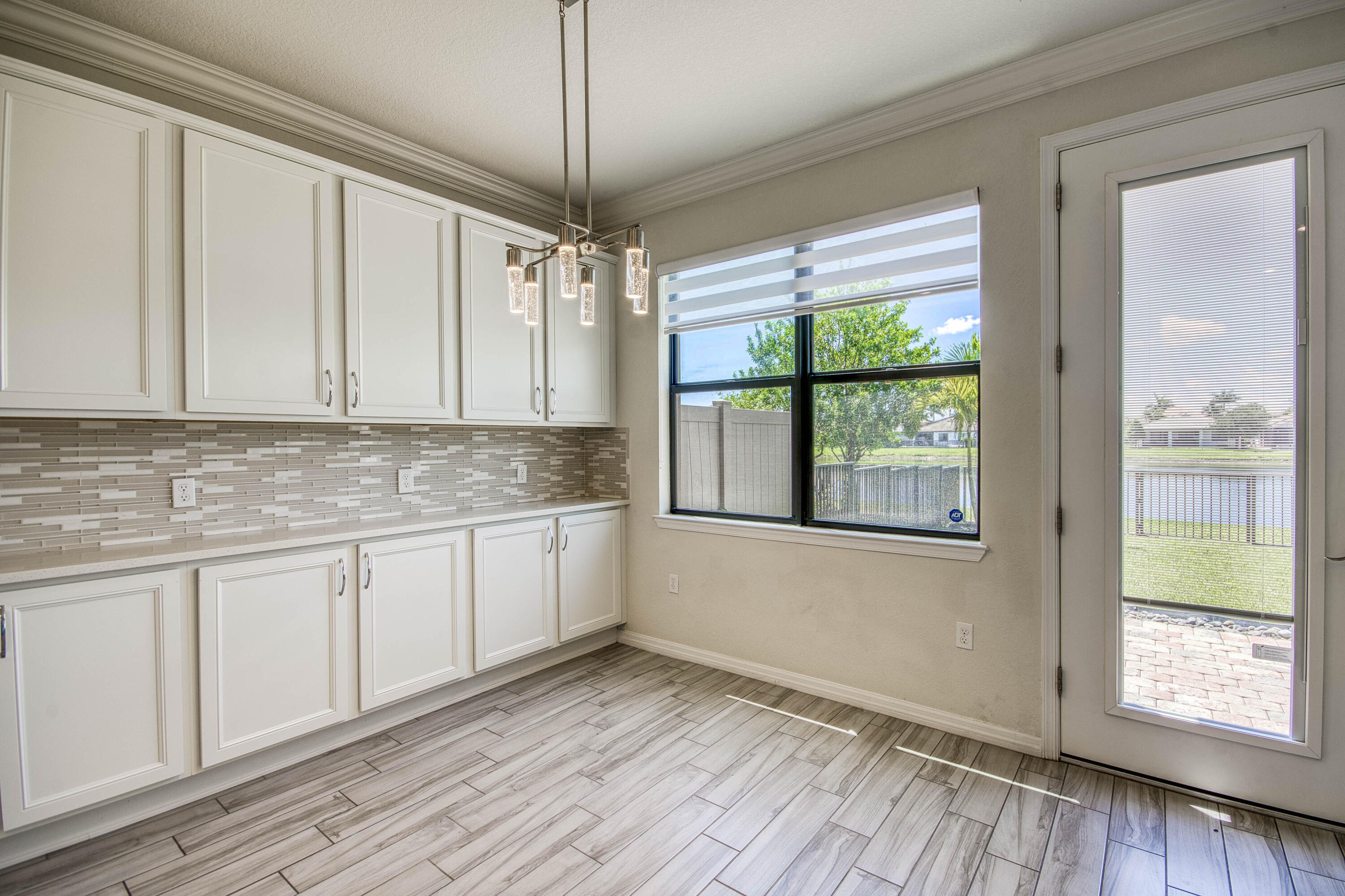 8301 Rearing Lane Lake Worth, FL 33467 - Photo 17 of 33 a kitchen with granite countertop wooden floors white cabinets and a large window