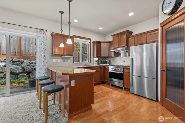 a kitchen with stainless steel appliances granite countertop a refrigerator a stove a sink dishwasher a oven with a dining table and chairs