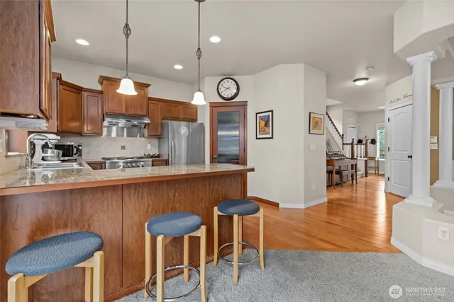 a kitchen with stainless steel appliances granite countertop a table chairs sink and wooden floor
