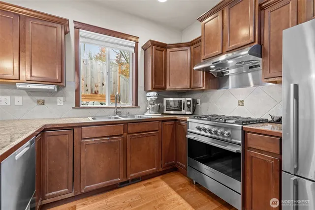 a kitchen with stainless steel appliances granite countertop a stove a sink and a refrigerator