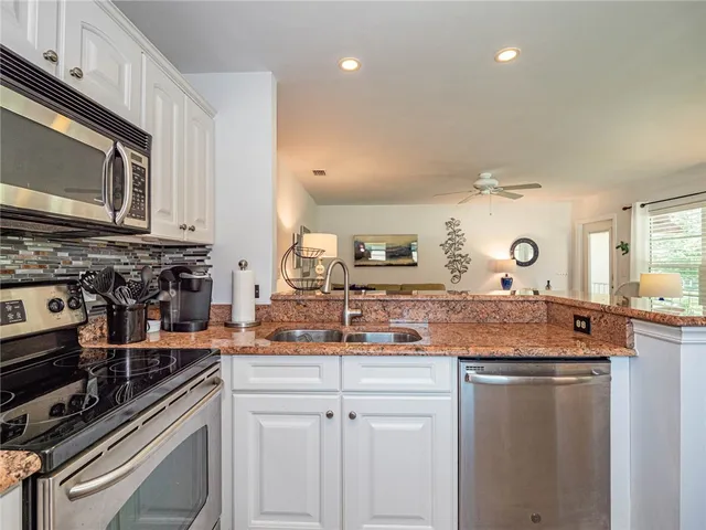 a kitchen with stainless steel appliances granite countertop a sink stove and cabinets