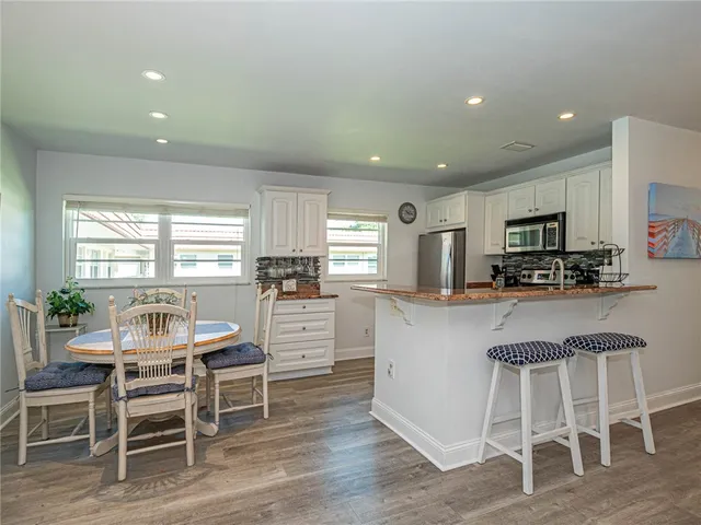 a kitchen with microwave a refrigerator and chairs