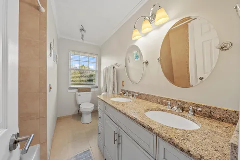 a bathroom with a granite countertop double vanity sink and a mirror