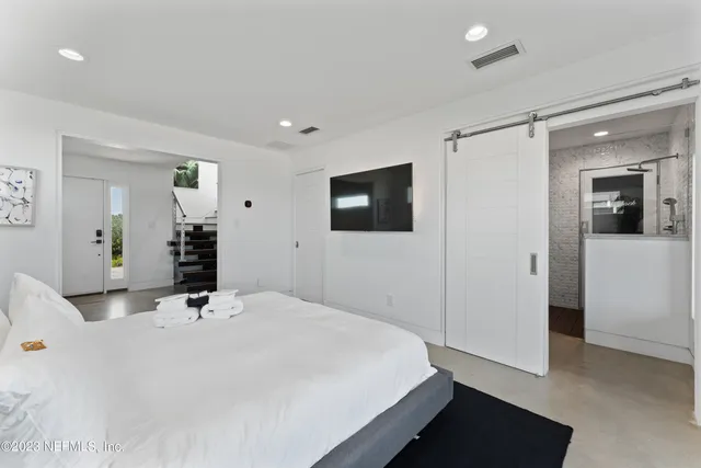 a bedroom with a large bed and a flat tv screen on dresser