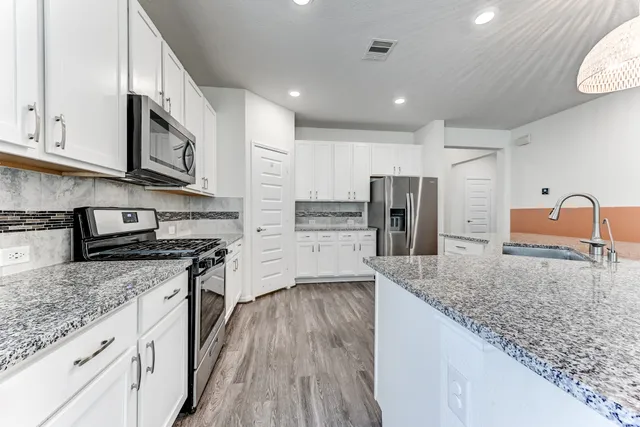 a kitchen with stainless steel appliances granite countertop a stove a sink and a refrigerator