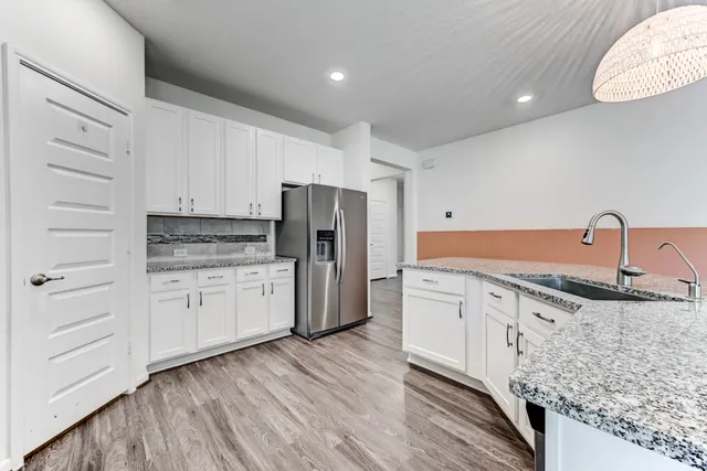 a kitchen with granite countertop white cabinets and stainless steel appliances