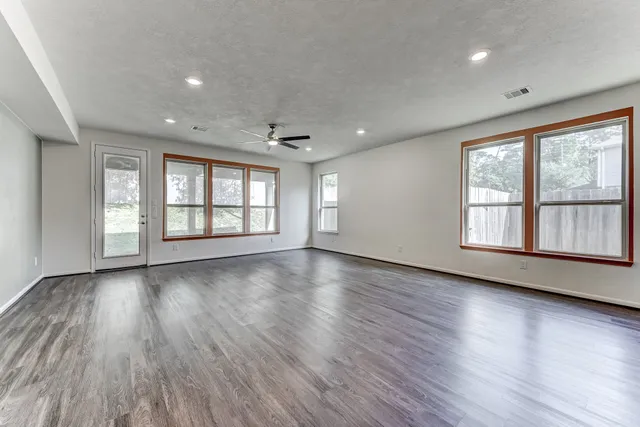 a view of an empty room with wooden floor and a window