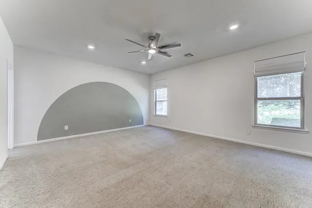 an empty room with a window and a ceiling fan