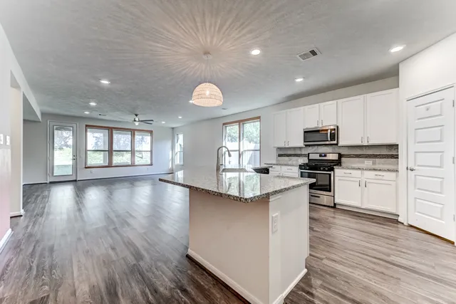 a kitchen with stainless steel appliances kitchen island granite countertop a stove top oven and cabinets