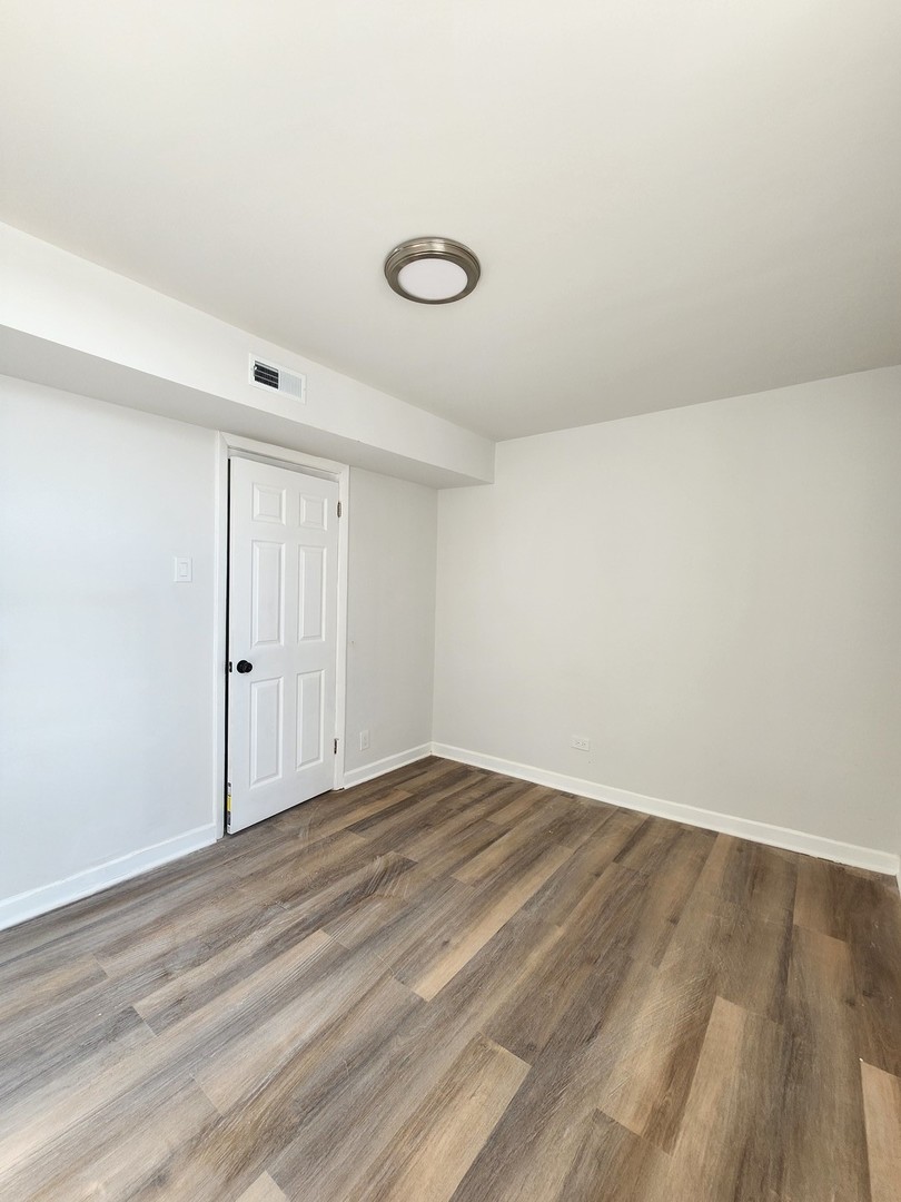 8900 South Normal Avenue, Unit 2 Chicago, IL 60620 - Photo 6 of 7 a view of an empty room with wooden floor and a window