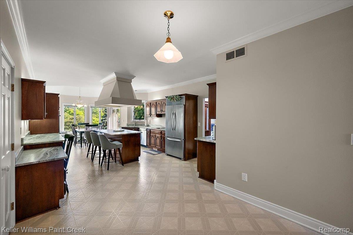 69069 Campground Road Romeo, MI 48065 - Photo 29 of 78 Open-concept kitchen featuring wood cabinetry, stainless steel appliances, a central island with seating, a large range hood, and patterned flooring