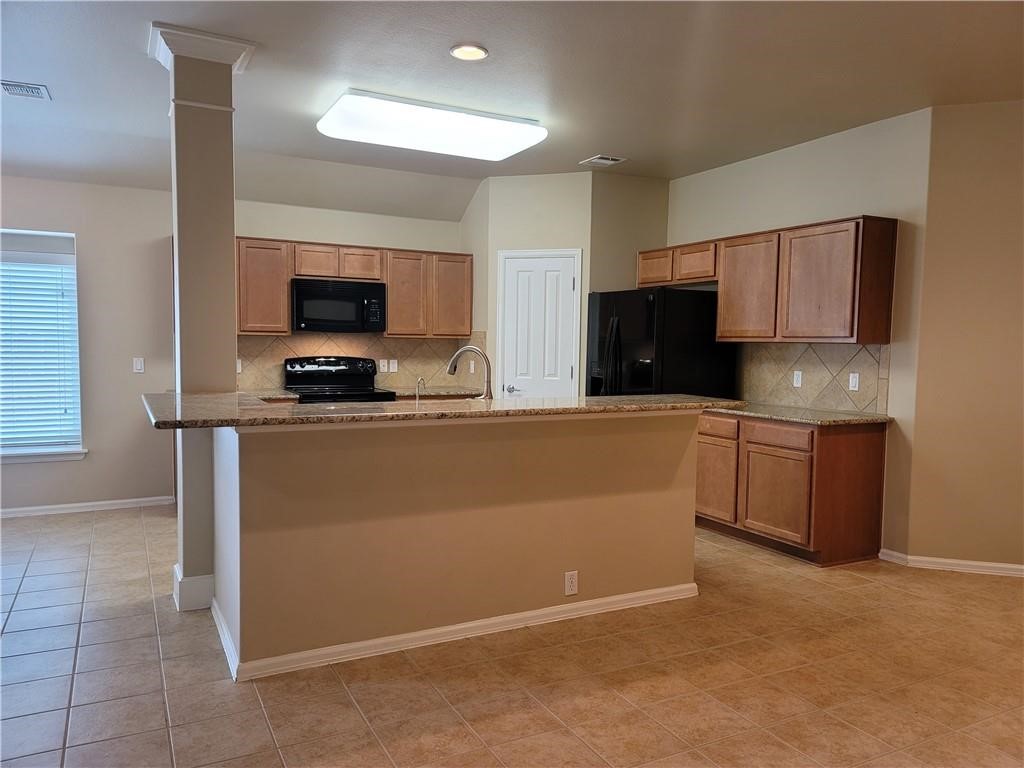 208 Hummingbird Lane Leander, TX 78641 - Photo 5 of 25 An inviting kitchen features a breakfast bar with granite counters, ideal for casual dining.