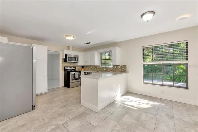 a kitchen with a refrigerator and white cabinets