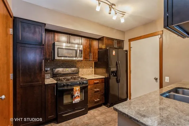 a kitchen with stainless steel appliances granite countertop a refrigerator a stove and a sink