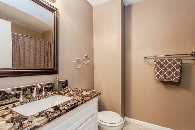 a bathroom with a granite countertop sink vanity mirror and toilet