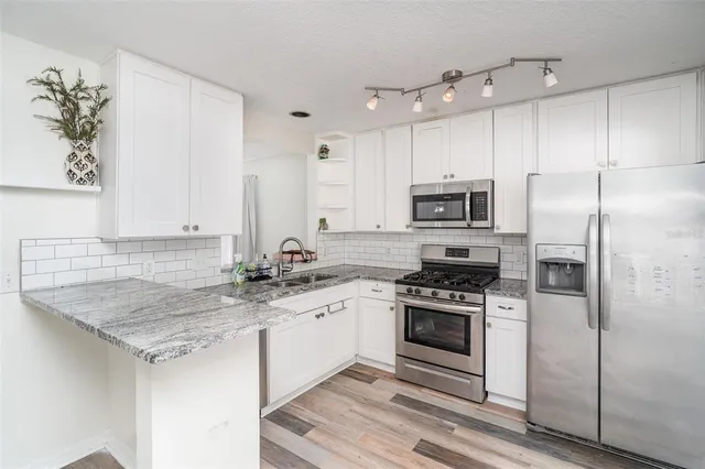 a kitchen with stainless steel appliances granite countertop a sink stove and refrigerator