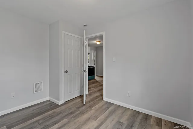 a view of an empty room with wooden floor and closet