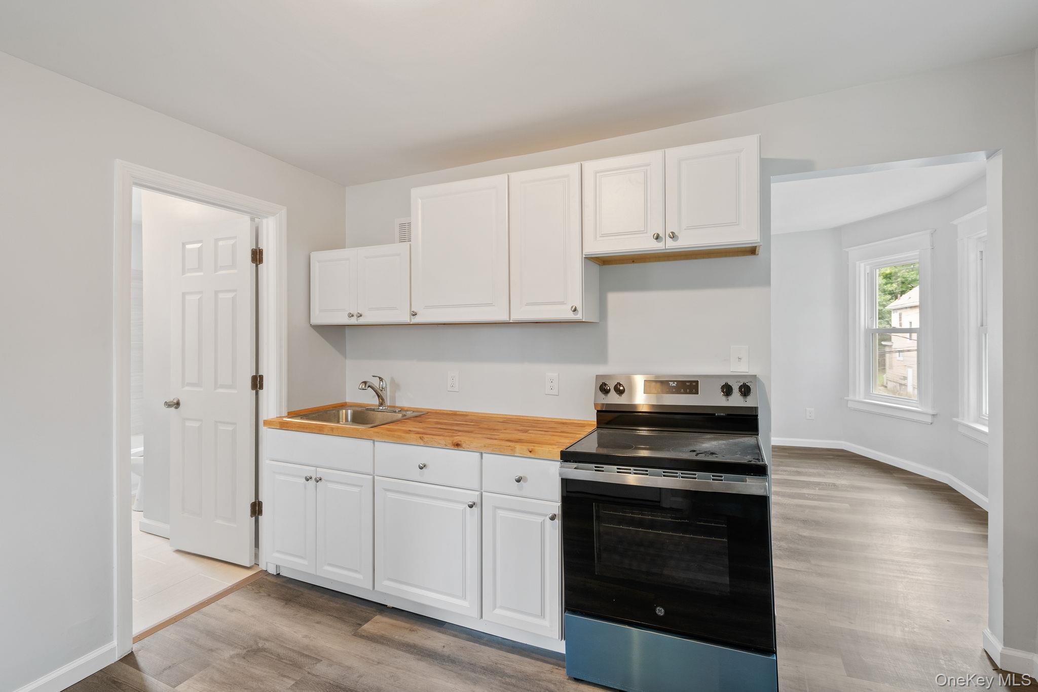 21 Lent Street Poughkeepsie, NY 12601 - Photo 31 of 47 Kitchen with stainless steel electric stove, white cabinetry, light wood-type flooring, and butcher block countertops