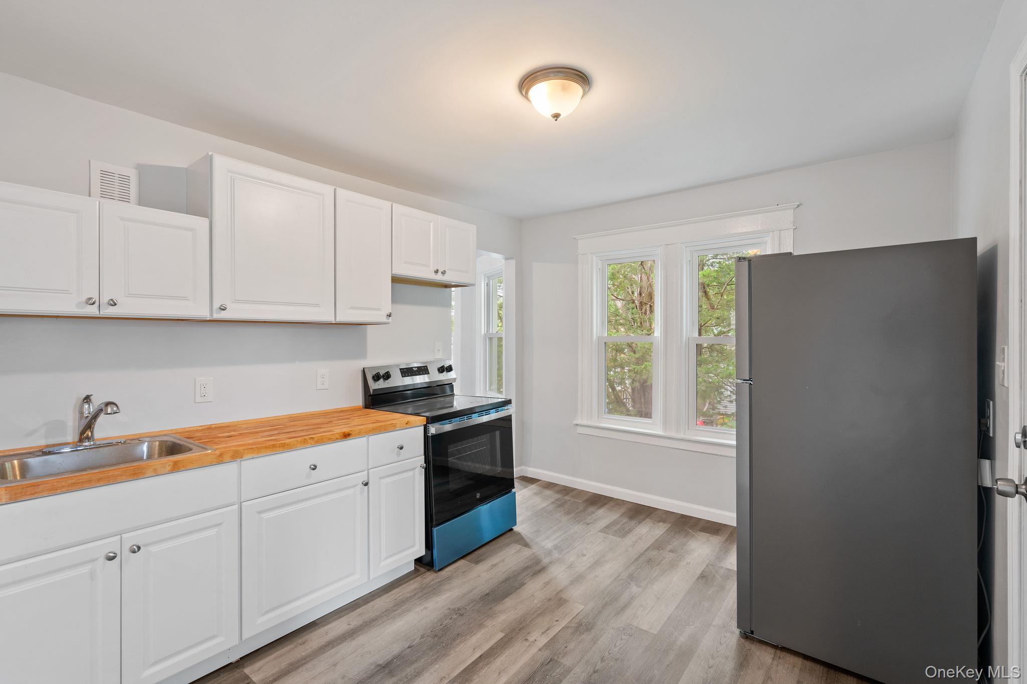 21 Lent Street Poughkeepsie, NY 12601 - Photo 32 of 47 Kitchen with appliances with stainless steel finishes, white cabinetry, light wood-type flooring, and butcher block countertops