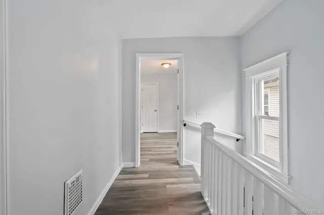 a view of a hallway with stairs and wooden floor