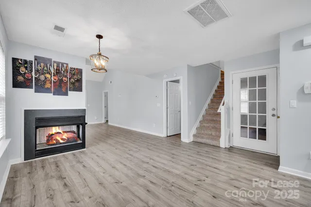 a view of an empty room with wooden floor fireplace and a window